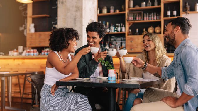 Young people sitting at cafe table and having coffee together.