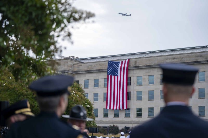 Members of the armed services look on as a plane takes off over a U.S. flag hanging from the Pentagon to mark the 22nd anniversary of the September 11 terrorist attacks there in Arlington, Va., on Monday. Photo by Bonnie Cash/UPI