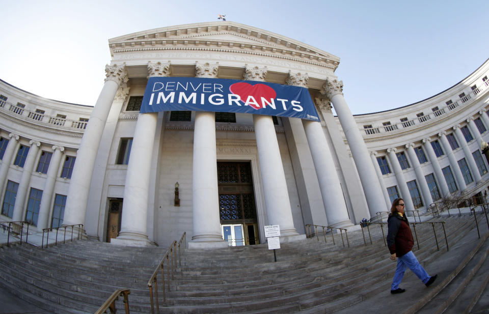 FILE - In this Feb. 26, 2018 file photo, a banner to welcome immigrants is shown through a fisheye lens over the main entrance to the Denver City and County Building. The U.S. Justice Department told The Associated Press at the end of February 2019 that 28 jurisdictions, including Denver, that were targeted in 2017 over what it considered "sanctuary" policies have been cleared for law enforcement grant funding. (AP Photo/David Zalubowski, File)