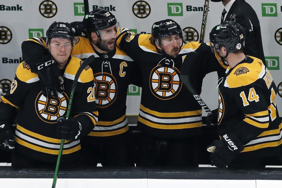 Boston Bruins' Curtis Lazar (20), Patrice Bergeron (37), Brad Marchand (63) and Chris Wagner (14) celebrate the impending win as the clock runs down at the end of Game 4 of the team's NHL hockey Stanley Cup first-round playoff series against the Washington Capitals, Friday, May 21, 2021, in Boston. (AP Photo/Michael Dwyer)