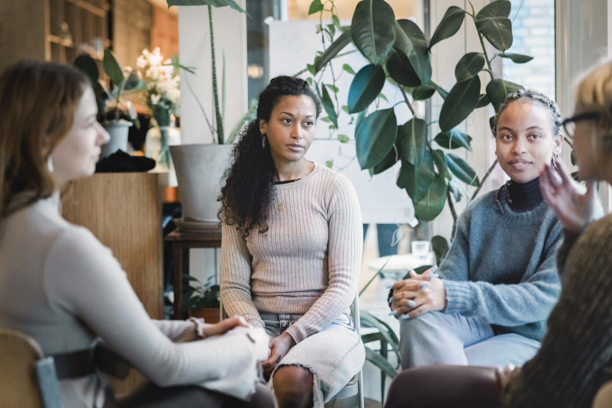 Multi-ethnic group of woman sitting in a group therapy session. Group of women listening to the story of therapist during support group meeting.