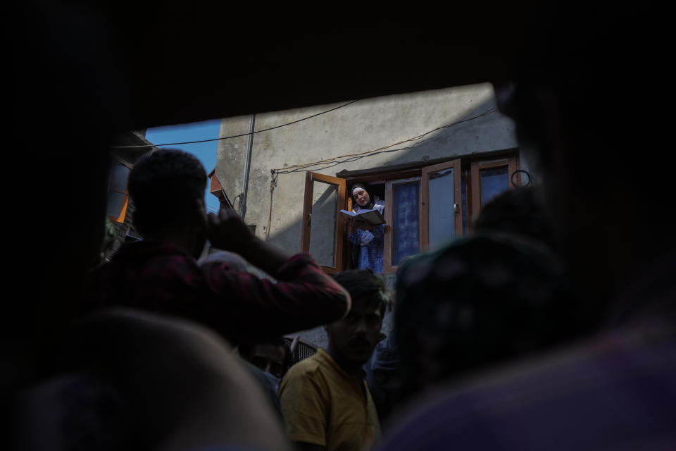 La gente escucha mientras Abida Malik, hermana del encarcelado líder separatista cachemir Yasin Malik, lee versos del Corán desde la ventana de su casa en Srinagar, en la Cachemira india, el 25 de mayo de 2022. (AP Foto/Mukhtar Khan)