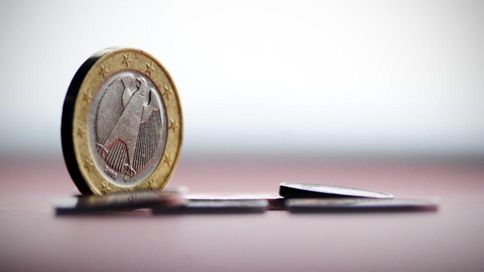Euro-Münzen liegen auf einem farbigen Papier.