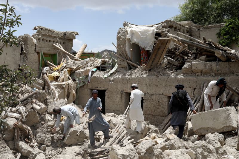 Afghan men search for survivors amidst the debris of a house that was destroyed by an earthquake in Gayan