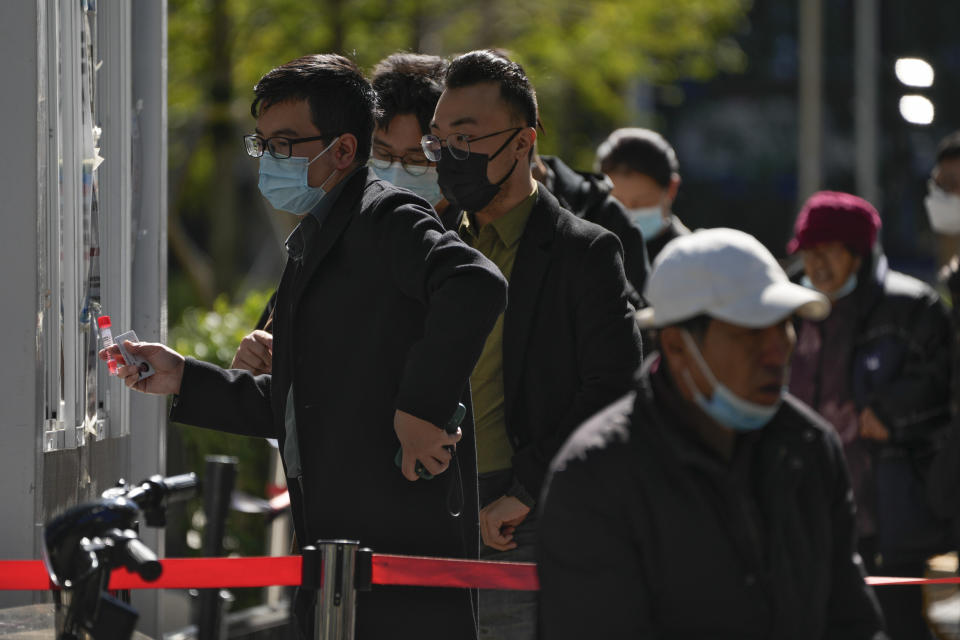 A man wearing a face mask collects his testing tube as masked residents line up to register to get their routine COVID-19 throat swabs at a coronavirus testing site in Beijing, Monday, Oct. 10, 2022. (AP Photo/Andy Wong)