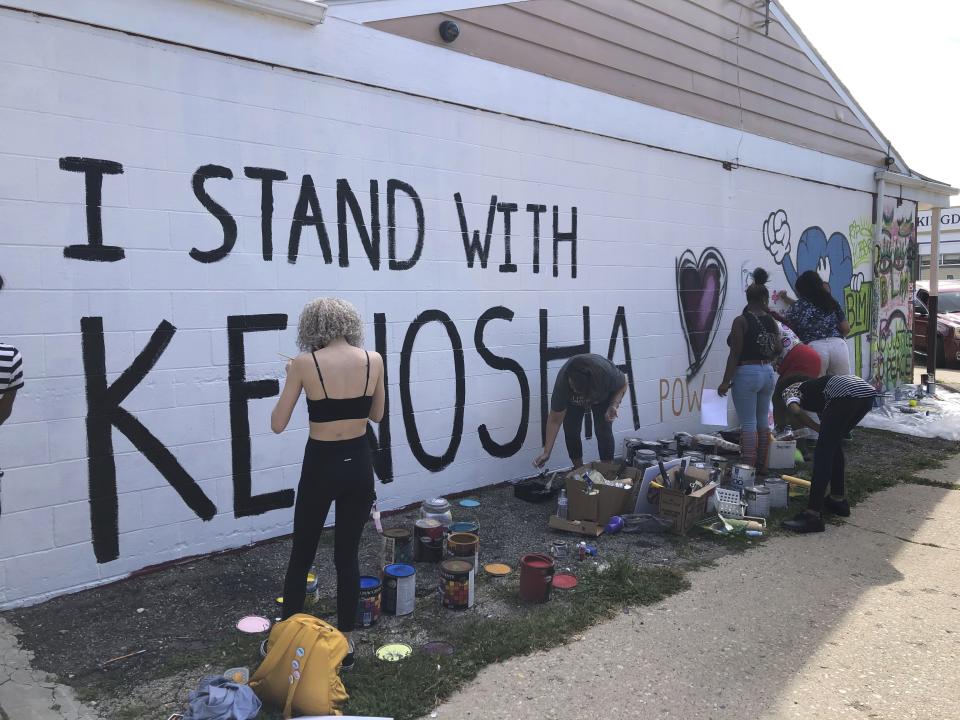 Volunteers paint murals on boarded-up businesses in Kenosha, Wis., on Sunday, Aug. 30, 2020, at an "Uptown Revival." The event was meant to gather donations for Kenosha residents and help businesses hurt by violent protests that sparked fires across the city following the police shooting of Jacob Blake. (AP Photo/ Russell Contreras)