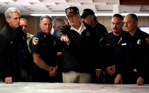 Donald Trump is briefed by emergency workers during his visit - Credit: Evan Vucci/AP