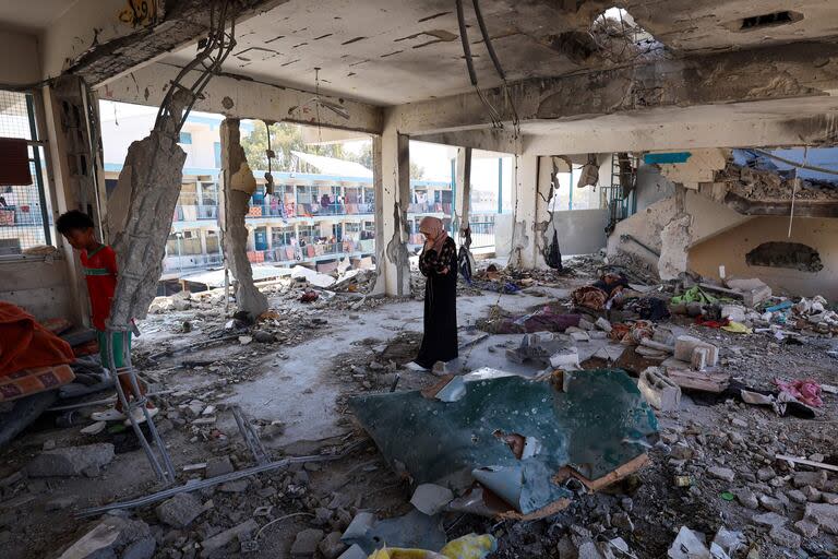 Una mujer palestina en medio de un aula destruida de una escuela gestionada por la Agencia de la ONU para los Refugiados Palestinos (UNRWA) que fue alcanzada durante un ataque del ejército israelí el día anterior, en el campamento de Nuseirat, en el centro de la Franja de Gaza, el 7 de junio de 2024, en medio del actual conflicto en el territorio palestino entre Israel y Hamas.