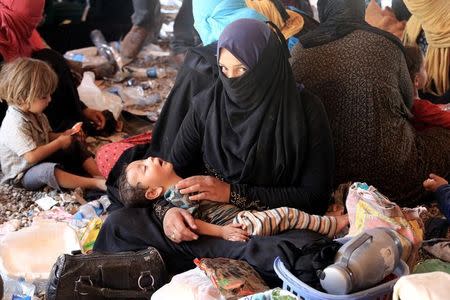 A displaced woman, who fled from Al-Shirqat, due to Islamic State violence, holds her child on the outskirts of Al-Shirqat, south of Mosul, Iraq, July 30, 2016. REUTERS/Stringer