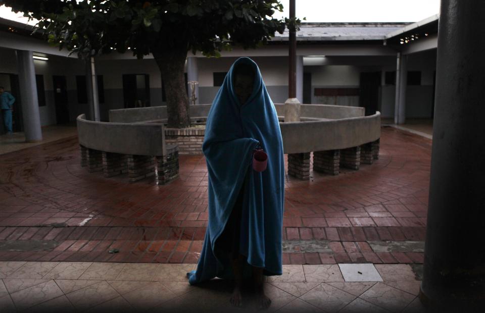 In this May 319, 2013 photo, a female patient at the Neuro-Psychiatric Hospital wears a blanket in the courtyard before breakfast in Asuncion, Paraguay. Despite the center's questionable conditions, for many patients it remains the only option. Doctors say 75 percent of the hospital's patients have been abandoned by their families. Many feel lucky to receive any kind of medical treatment, even if the system is broken. (AP Photo/Jorge Saenz)