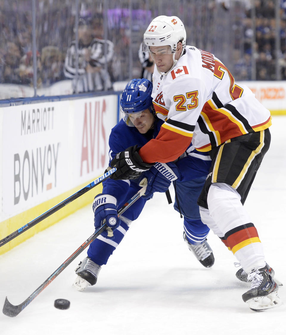 Calgary Flames centre Sean Monahan (23) ties up Toronto Maple Leafs left wing Zach Hyman (11) along the boards during the second period of an NHL hockey game Thursday, Jan. 16, 2020, in Toronto. (Nathan Denette/The Canadian Press via AP)