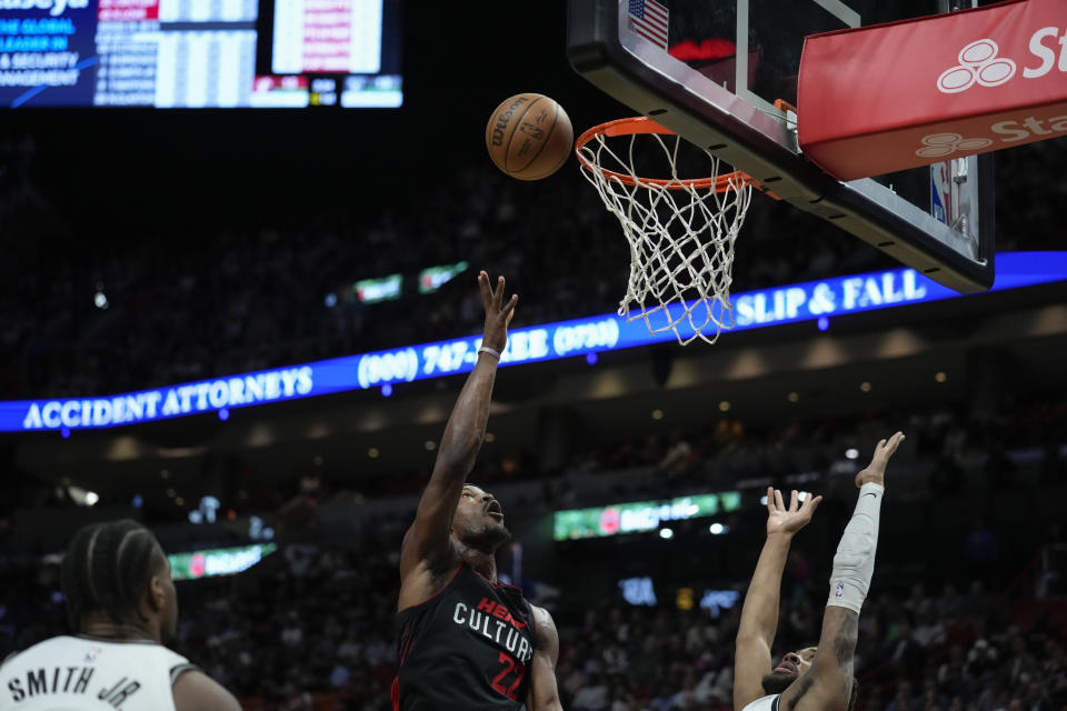 Miami Heat forward Jimmy Butler (22) shoots a basket over Brooklyn Nets guard Lonnie Walker IV, right, and guard Dennis Smith Jr., left, during the first half of an NBA basketball game, Thursday, Nov. 16, 2023, in Miami. (AP Photo/Rebecca Blackwell)