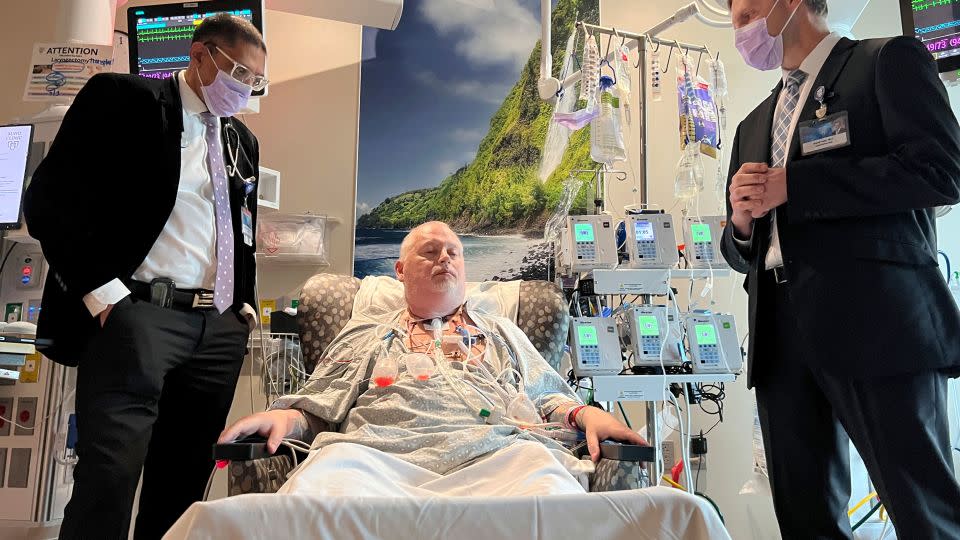 Dr. Girish Mour, left, medical director of Mayo Clinic's Larynx and Trachea Transplant Program, and Dr. David Lott, right, stand on either side of Marty Kedian on March 8, one week after his transplant surgery in Phoenix. - Mayo Clinic via AP