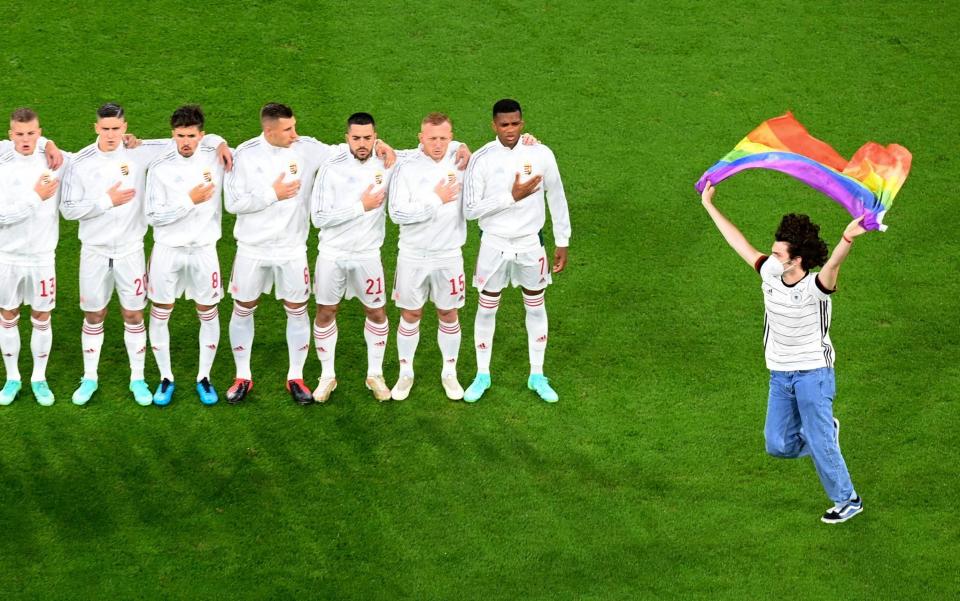 A protestor holding a rainbow flag runs onto the pitch in front of the Hungarian team before the Euro 2020 soccer championship group F match between Germany and Hungary at the football arena stadium in Munich - POOL GETTY