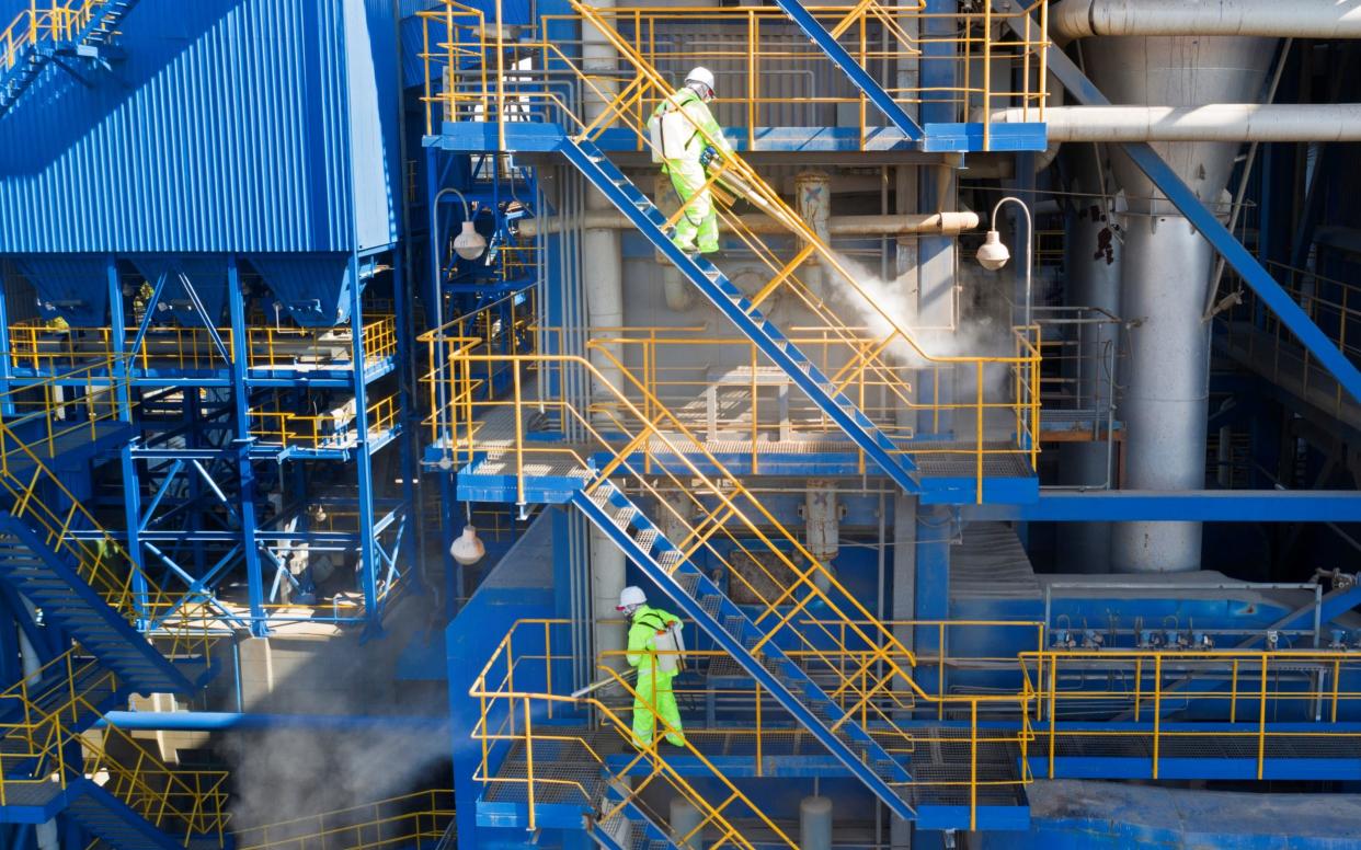 Volunteers in protective suits disinfect a factory with sanitising equipment in Huzhou, China -  CHINA DAILY/REUTERS