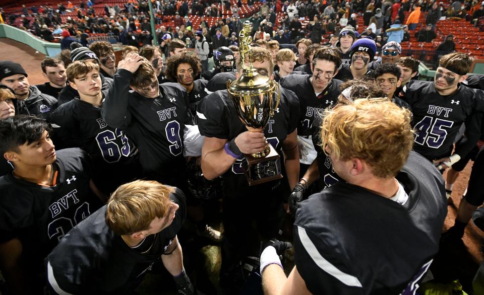 Blackstone Valley Tech captain John Furno kisses the Battle of Pleasant Street trophy as he and his teammates celebrate the 47-19 win over Nipmuc Regional at Fenway Park, Nov. 24, 2021.