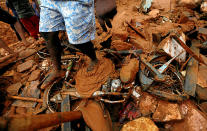 <p>A man stands on top of a damaged bike during a rescue mission at the site of a landslide in Bellana village in Kalutara, Sri Lanka, May 26, 2017. (Dinuka Liyanawatte/Reuters) </p>