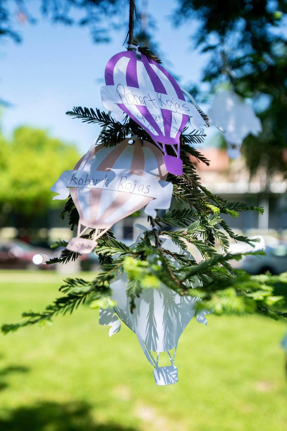 Paper balloons hang from a tree containing messages and the names of victims of violence and crime during the Merced County Victims’ Rights Ceremony at Courthouse Park in Merced, Calif., on Tuesday, April 25, 2023. The annual event held to remember victims of violence and crime, is hosted by the Merced County District Attorney’s Office during National Crime Victims’ Rights Week.