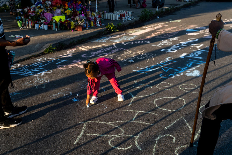 Adiyah Kijani, 2, adds a message to the memorial along the help of her father, right, Zahir Kijani, and his friend, Anthony Pierce, left, in Buffalo, N.Y. on May 15, 2022. (Joshua Thermidor for NBC News)