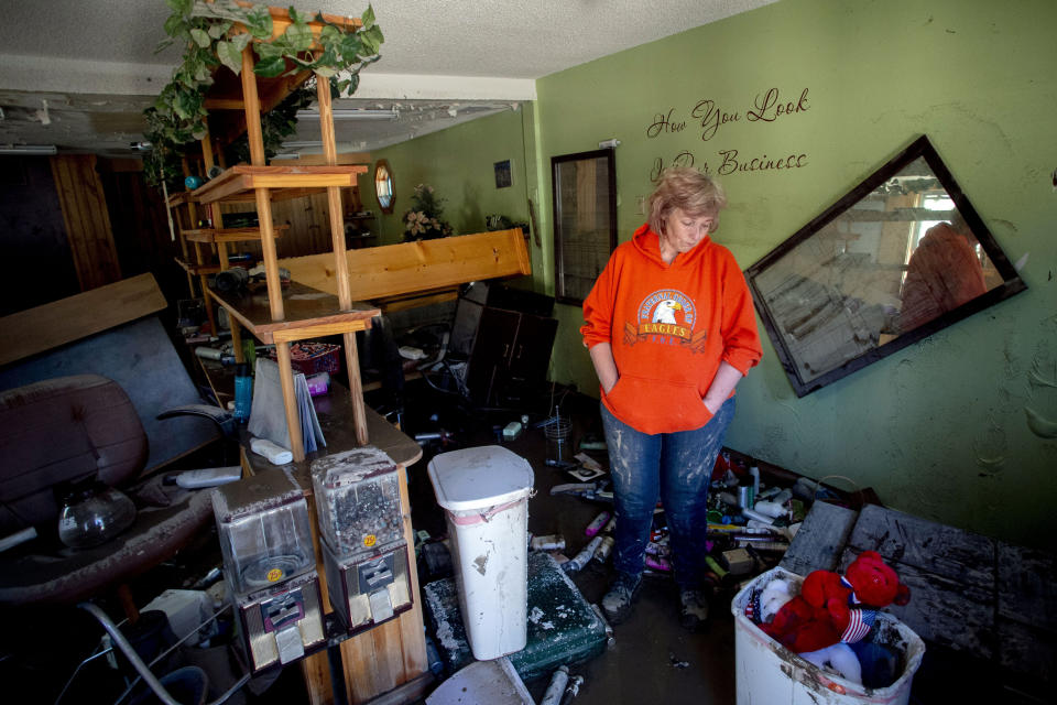 FILE - In this May 21, 2020 file photo, Sanford resident Connie Methner, owner of CJ's Hairstyling, bows her head as she copes with the damage after water flooded her salon to its ceiling in Sanford, Mich. Sanford village, with a population of 859, is pulling together after the devastation of two dam failures in May. Volunteers are still clearing muck and providing supplies to those whose homes were destroyed since there's no telling when major state and federal help will come. (Jake May/MLive.com/The Flint Journal via AP File)