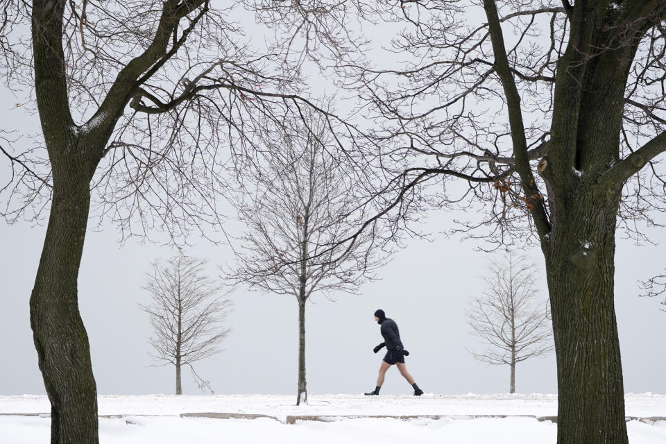 A lone runner leans into a stiff wind near Lake Michigan on the Northside of Chicago Tuesday, Jan. 26, 2021. A major winter storm dumped more than a foot of snow on parts of the middle of the country stretching from central Kansas northeast to Chicago and southern Michigan.(AP Photo/Charles Rex Arbogast)