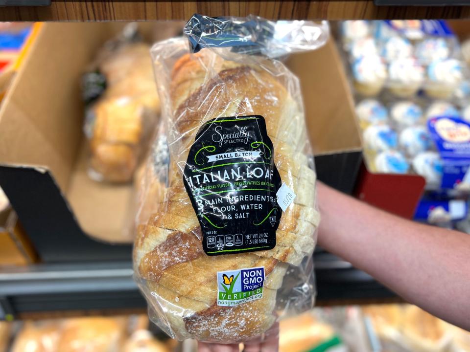 A hand holding a loaf of Specially Selected small-batch Italian bread.