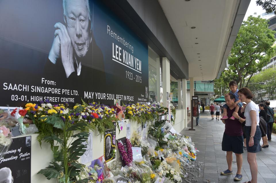 A family looks on in front of a memorial portrait of Singapore's late former prime minister Lee Kuan Yew outside the parliament building where he lies in state ahead of his funeral in Singapore on March 28, 2015. Singapore's first prime minister Lee Kuan Yew, one of the towering figures of post-colonial Asian politics, died at the age of 91 on March 23. AFP PHOTO / ADEK BERRY        (Photo credit should read ADEK BERRY/AFP via Getty Images)