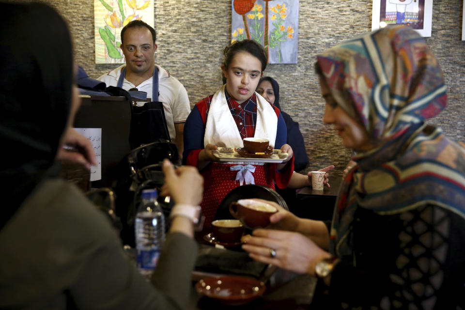 In this Monday, Aug. 6, 2018, photo, cafe staff Melika Aghaei, 14, with down syndrome, center, works in Downtism Cafe in Tehran, Iran. The popular cafe, whose name combines “Down” with “autism,” in Tehran’s bustling Vanak Square is entirely run by people with Down syndrome or autism. More than just providing meaningful work, the cafe is helping break down barriers by highlighting how capable people with disabilities are. (AP Photo/Ebrahim Noroozi)