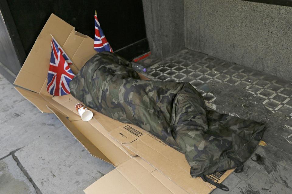 A homeless person lays on cardboard decorated with Union Flags in central London: Reuters