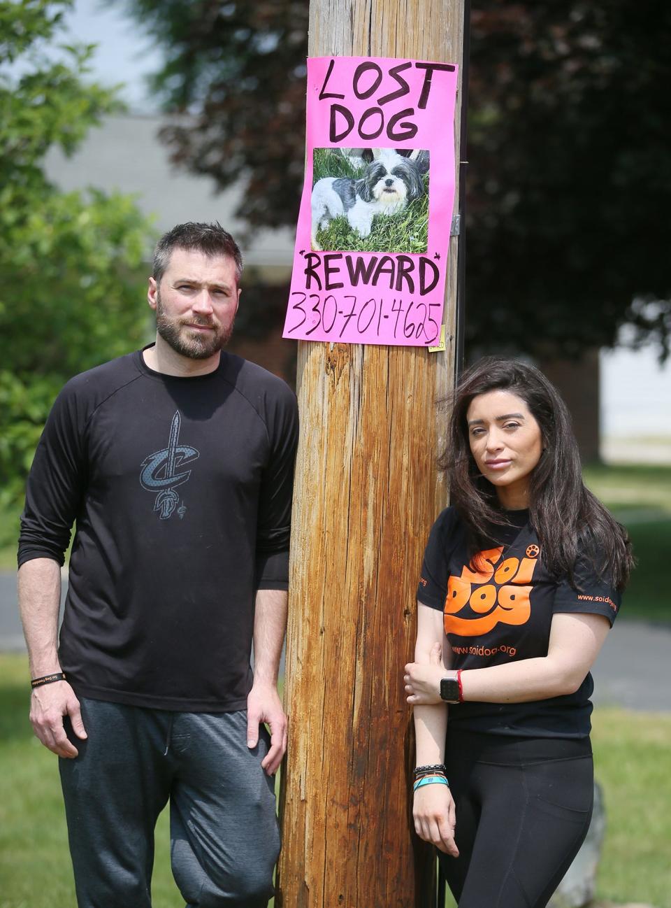 Justin and Nia Couch stand near a poster for their lost Shih Tzu in front of their home in Copley. The dog was later found 3 miles from their home.