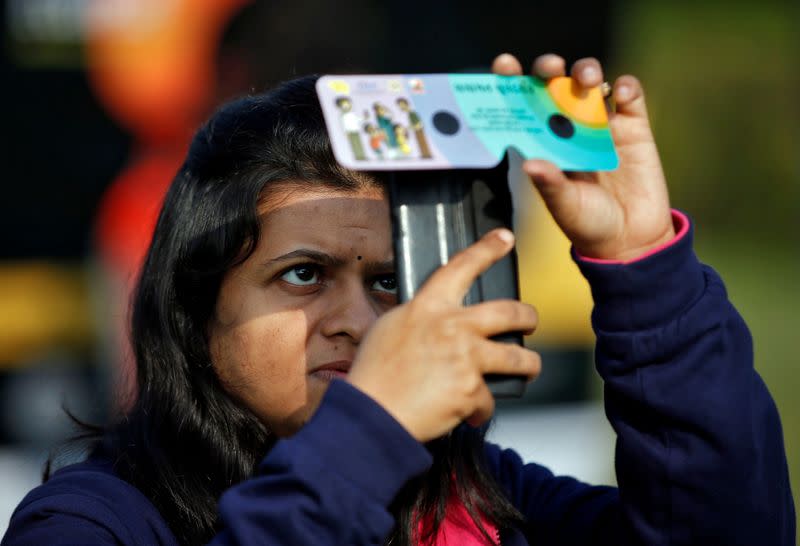 A woman uses her mobile phone and solar viewers to take photographs of the annular solar eclipse in Ahmedabad