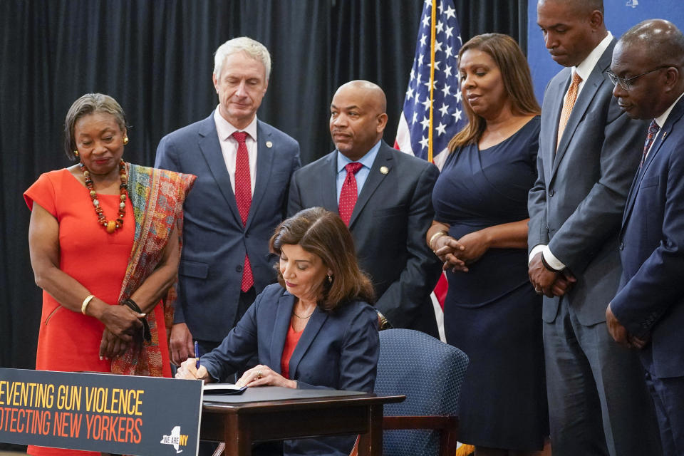 New York Gov. Kathy Hochul, center, signs a package of bills to strengthen gun laws, Monday, June 6, 2022, in New York. New York has strengthened gun laws as part of a series of laws signed this week by Gov. Kathy Hochul with the hope to lessen gun violence and gun-related deaths. Hochul, a Democrat, signed 10 gun-related bills Monday. (AP Photo/Mary Altaffer)