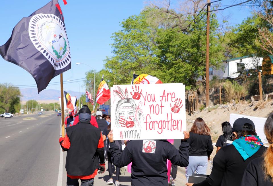 Community members carry signs with messages about the crisis of missing and murdered Indigenous women during an awareness walk on May 5, 2021 in Shiprock.