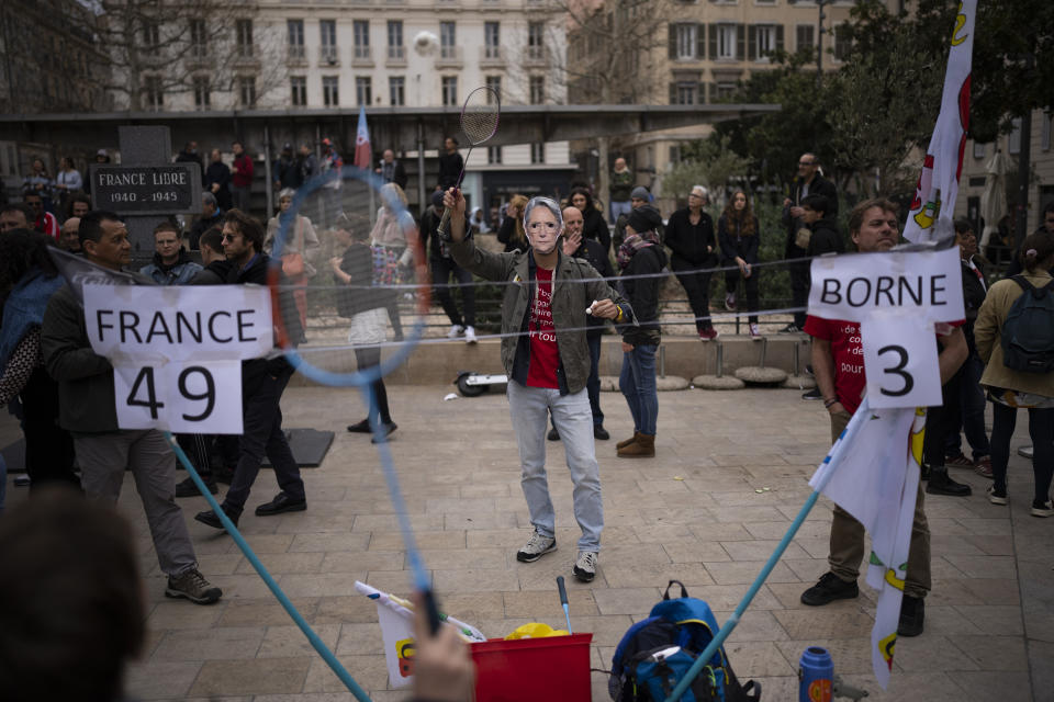 A protester wearing a mask depicting French Prime Minister Elisabeth Borne plays badminton during a demonstration in Marseille, southern France, Saturday, March 18, 2023. A spattering of protests are planned to continue in France over the weekend against President Emmanuel Macron's controversial pension reform. (AP Photo/Daniel Cole)