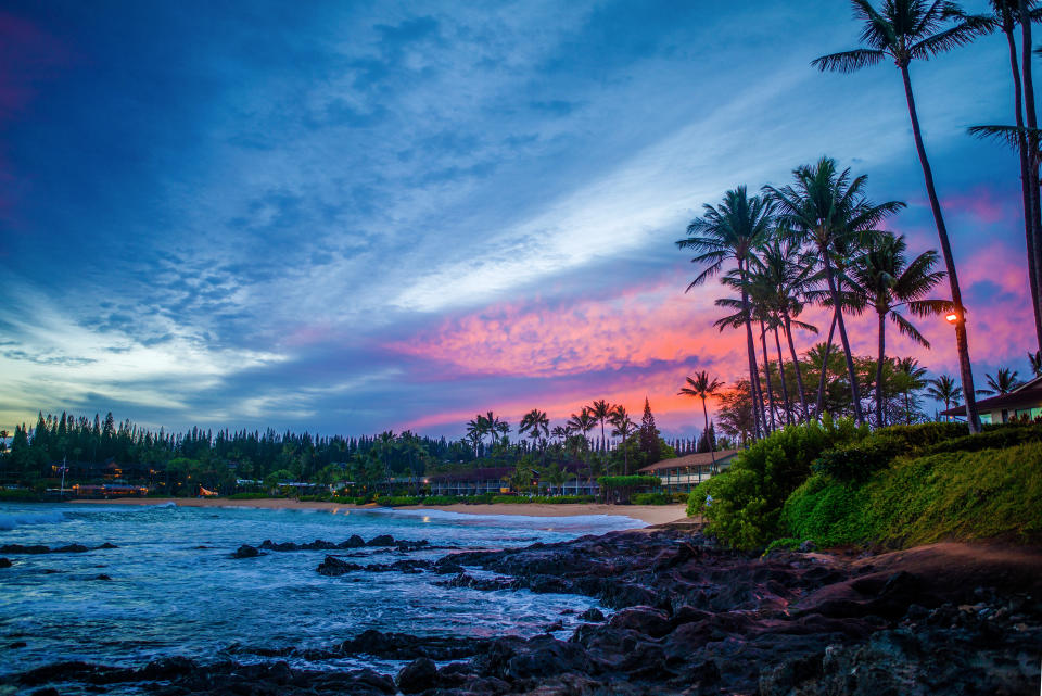 a glowing pink sunrise over the rocky lava and sandy beach, of napili bay, maui, hawaii