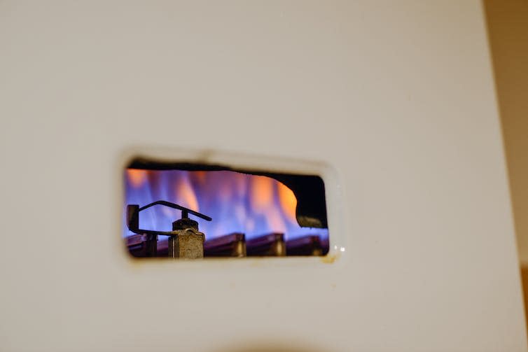 The white cover of a gas boiler with the pilot light visible.