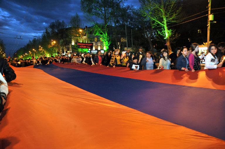 Armenians carry the national flag to commemorate the 99th anniversary of the Ottoman Turkish massacre of Armenians, during a ceremony in Yerevan, on April 23, 2014