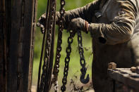 A well worker moves equipment at a site on the Rooke family ranch where an orphaned oil well was plugged, Tuesday, May 18, 2021, near Refugio, Texas. Oil and gas drilling began on the ranch in the 1920s and there were dozens of orphaned wells that needed to be plugged for safety and environmental protection. (AP Photo/Eric Gay)