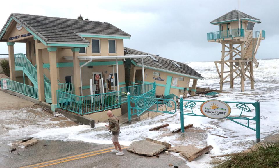 A storm watcher checks out the damage to the Volusia County Beach Safety office at the Dunlawton beach ramp, Wednesday, Nov. 9, 2022 as Tropical Storm Nicole moves closer.