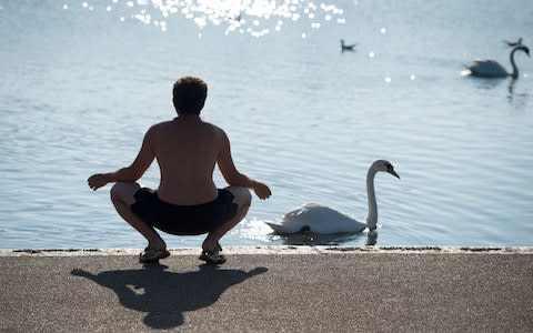 A man enjoys the warm weather by the pond in Kensington Gardens, London - Credit: Dominic Lipinski /PA