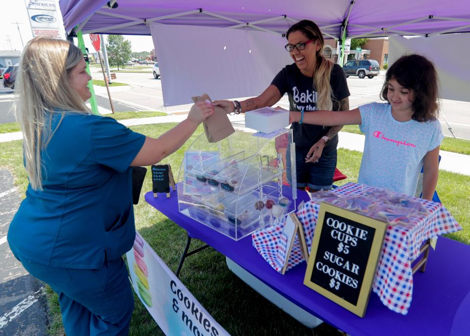 Katrina Kroeplin and her daughter, Fallon Gehman, serve Miranda Mroczenski on July 2 at Prevail Bank in Marshfield. Kroeplin owns and operates Kat's Sweet Escape, a home baking business.