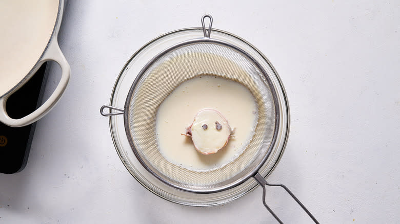 straining sauce into bowl