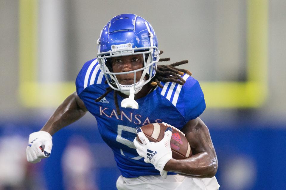 Kansas redshirt sophomore wide receiver Douglas Emilien runs with the ball during a fall camp practice one evening this year at the indoor practice facility.