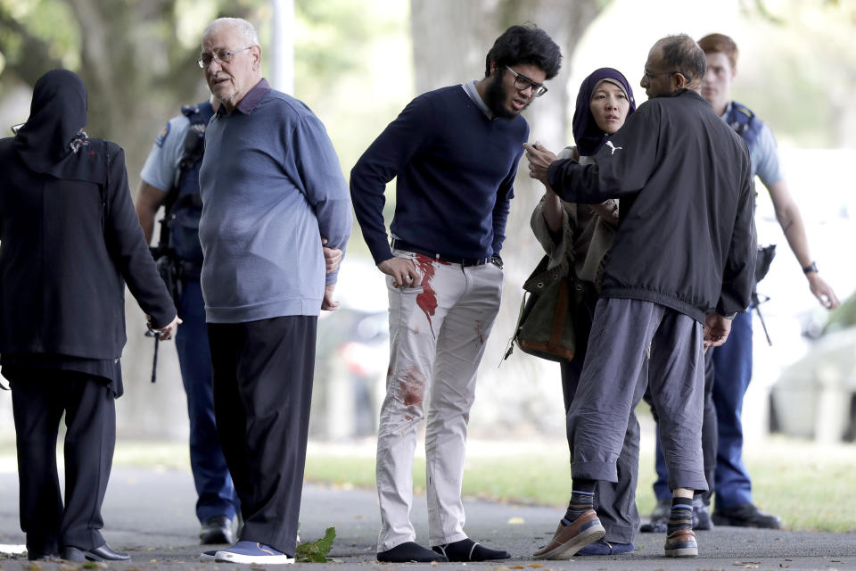 FILE - In this March 15, 2019, file photo, people stand across a road from the Al Noor mosque following a mass shooting in central Christchurch, New Zealand. On Sunday, March 15, 2020, New Zealand will commemorate the 51 people who were killed in the attacks. (AP Photo/Mark Baker, File)