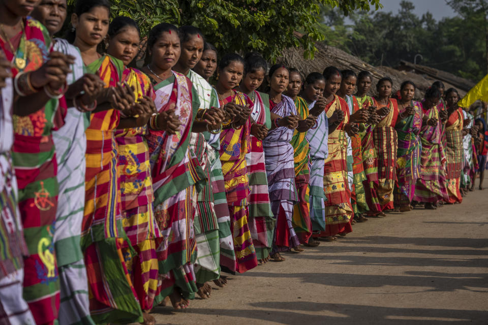 Tribes women dressed up in colorful saris perform indigenous folk dance as they follow worshippers to a sacred grove believed to be the home of the village goddess, in village Guduta, in the eastern Indian state of Odisha, Oct. 21, 2022. India's 110 million indigenous tribespeople scattered across various states and fragmented into hundreds of clans, with different legends, different languages and different words for their gods adhere to Sarna Dharma - a faith not officially recognized by the government. It is a belief system that shares common threads with the world's many ancient nature-worshipping religions. (AP Photo/Altaf Qadri)