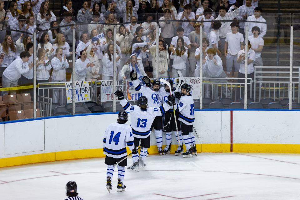 Members of the Oyster River boys hockey team celebrates with the student section after scoring just 47 seconds into Saturday's Division II state championship game at Southern New Hampshire University Arena in Manchester.