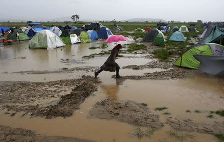 A woman holding an umbrella walks in a flooded field during heavy rainfall at a makeshift camp for refugees and migrants at the Greek-Macedonian border near the village of Idomeni, Greece, May 21, 2016. REUTERS/Kostas Tsironis