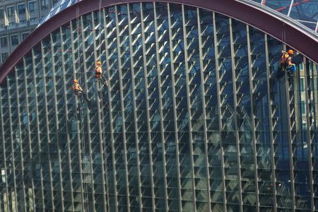 Workers clean windows overlooking Docklands Light Railway in Canary Wharf, London, Britain July 5, 2017. REUTERS/Dylan Martinez