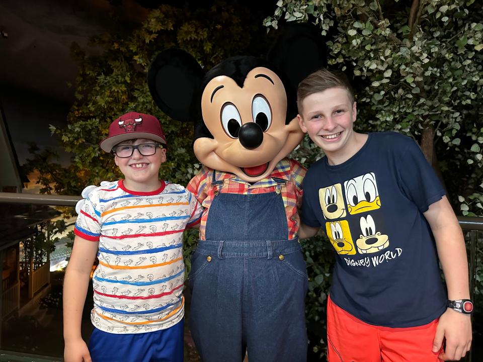kari's sons posing with mickey mouse at garden grill in epcot at disney world