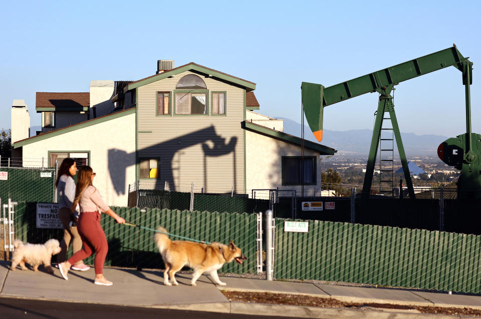 SIGNAL HILL, CALIFORNIA - FEBRUARY 09: An oil price pumpjack stands idle near homes as people walk with dogs on February 09, 2023 in Signal Hill, California. California law S.B. 1137, which required a safety buffer zone of 3,200 feet around homes and schools for new oil and gas drilling, was suspended after the petroleum industry collected enough signatures in a petition campaign to place a referendum on the 2024 general election ballot. The bill was originally signed into law by Governor Gavin Newsom last year and also banned new drilling near parks, health care facilities, prisons and businesses open to the public. (Photo by Mario Tama/Getty Images)